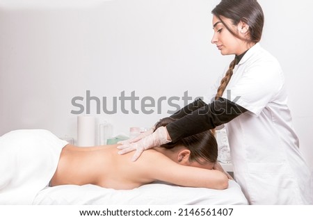 Young woman lying on a stretcher receiving a back massage in a physiotherapy center. High quality photo