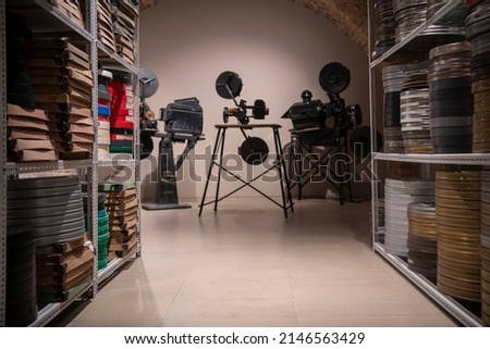 Vintage photo of cinema library with old video movie projectors and film reels on shelves.