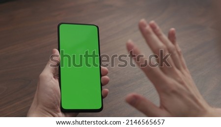man using smartphone with for online communication on walnut table