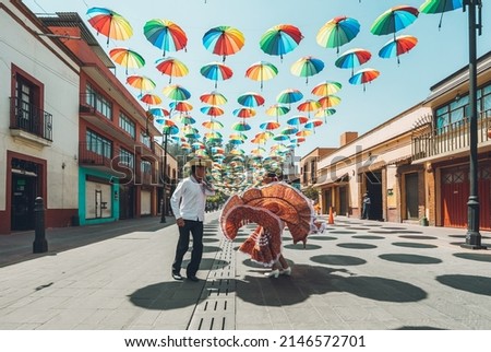 Dancers of typical Mexican dances from the central region of Mexico, doing their performance in the street adorned with colored umbrellas. Royalty-Free Stock Photo #2146572701