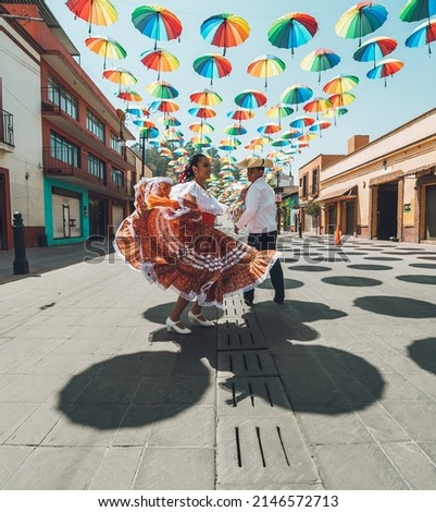 Dancers of typical Mexican dances from the central region of Mexico, doing their performance in the street adorned with colored umbrellas. Royalty-Free Stock Photo #2146572713
