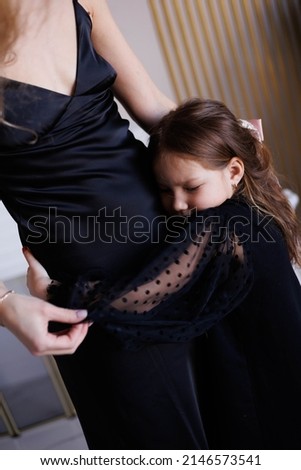 Lovely family mother and daughter embracing and kissing each other at home. Happy sweet woman with little 6-year-old girl in black dresses, family look, hugging and smiling