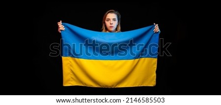Beautiful Ukrainian girl with the national state flag of Ukraine on black background. Copy space. Russian Ukrainian War. Help and Pray for Ukraine. Stop war.