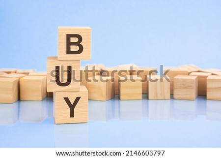 on a bright pale lilac and blue background, light wooden blocks and cubes with the text BUY. cubes is reflected from the surface