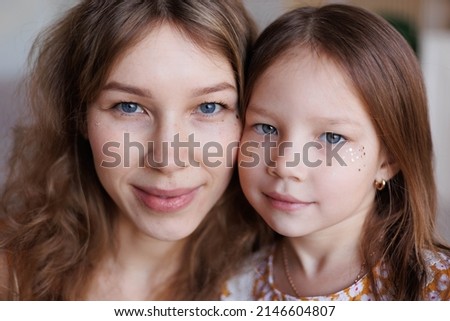 Portrait of lovely family mother and daughter embracing and kissing each other at home. Happy sweet woman with little 6-year-old girl in yellow dresses, family look, sitting on floor. Sweet family