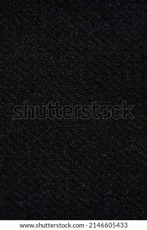 Macro clean bright photo of the black textured cotton and denim fabric of blouse and shirt. Pattern and background for fashion and textile production.