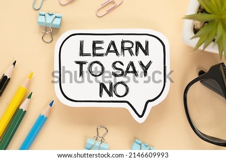 LEARN TO SAY NO written in a white notebook on a light wooden background near a calculator, a cup of coffee, glasses and a pen. Flat lay. Motivating concept