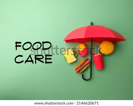 Top view umbrella and fast food toys with text FOOD CARE on green background