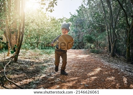 Chaaarge. Portrait of an adorable little boy playing with a cardboard sword and shield outside. Royalty-Free Stock Photo #2146626061