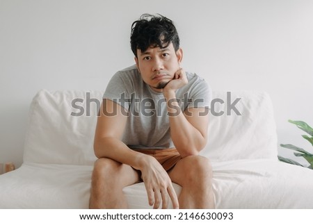 Asian man feels bored with his boring life sit on the sofa in his apartment.