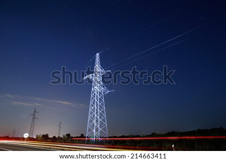 Pylon for electricity distribution at night with car lights in front
