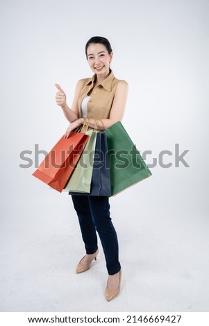 Woman holding paper bags with smile on white background in shopping concept.