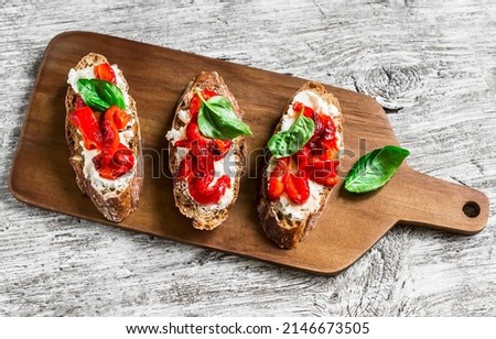 Bruschetta with feta cheese, roasted red sweet peppers and basil on a light wooden background            Royalty-Free Stock Photo #2146673505