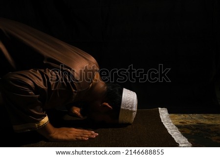 A picture of men perform "sujud" on praying mat during at night. Sign of devout and repent to Allah.