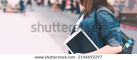 Traveller woman hand holding tablet at outdoor for online digital application. Black blank device screen banner size background with copy space. Royalty-Free Stock Photo #2146692297