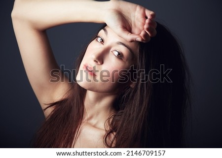 Elegant Beauty. Portrait of a beautiful brunette with her hands to her forehead.