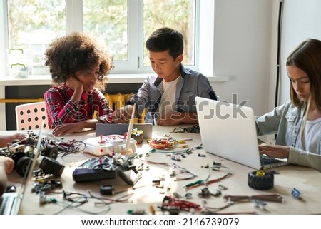 Afro American girl and Asian boy schoolkids using tablet device developing program for software robotics engineering and building at school lab. AI technologies development. STEM education. Vertical. Royalty-Free Stock Photo #2146739079