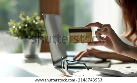 Asian woman checking online order details on computer and use the credit card information entered on the computer.
