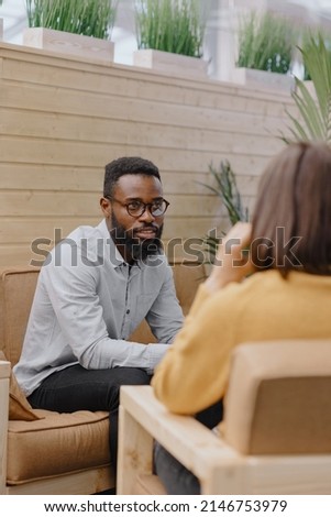 a male psychologist conducts a patient's appointment in an office or a medical center. African American male HR conducts an interview of hiring a European woman. business meeting or solving work tasks Royalty-Free Stock Photo #2146753979