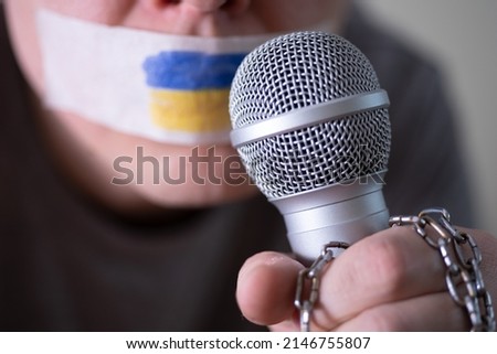 Tape over his mouth with the flag of Ukraine, trying to speak into a microphone. The concept of freedom of the press in Ukraine.