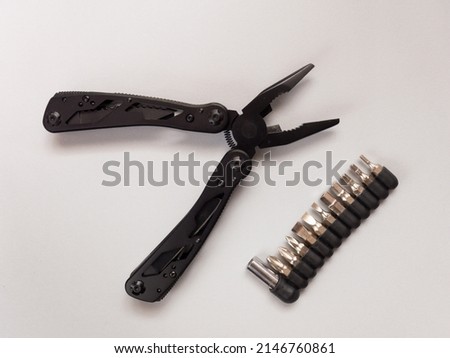 Pasatizhi in the form of multi-tools are laid out on a gray surface, next to it lies a set of tip screwdrivers. Royalty-Free Stock Photo #2146760861