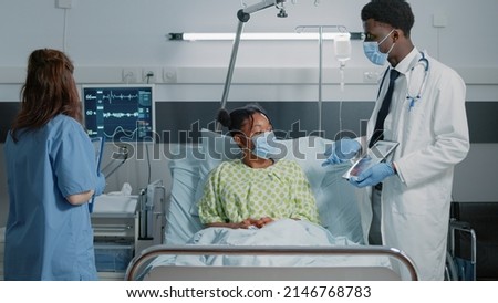 Physician pointing at tablet with cardiology diagnosis to explain disease to woman during pandemic. Doctor showing cardiovascular image on display to give medical assistance to patient