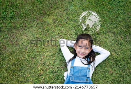 Top view of cute asian little girl on the green grass and she is happy thinking about love, friend, freedom, peaceful, diversity and connectivity of people around the world and save the world concept. Royalty-Free Stock Photo #2146773657