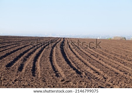 Ploughed field in spring, agricultural background, fog over the city in the background. Ukraine.