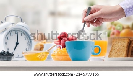 Woman having a delicious breakfast at home, she is stirring tea