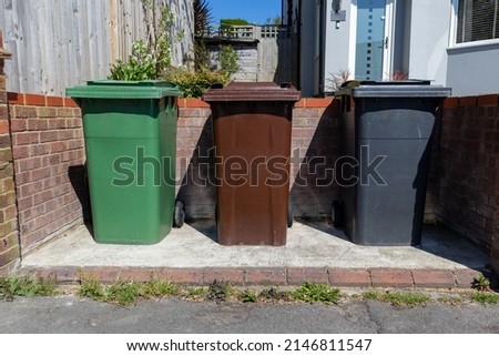Three wheelie bins for recycling, waste and garden waste neatly arranged in a urban front garden Royalty-Free Stock Photo #2146811547