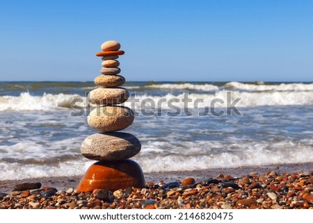 Zen pyramid of balanced stones on a background of the summer sea and blue sky. Concept of spiritual harmony, balance and meditation