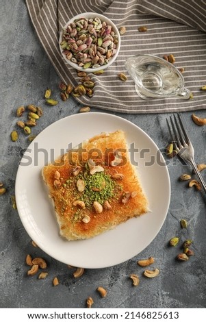Homemade arabian traditional sweets Kunafa or konafa nuts on top, cheese and sugar syrup, on tray Royalty-Free Stock Photo #2146825613
