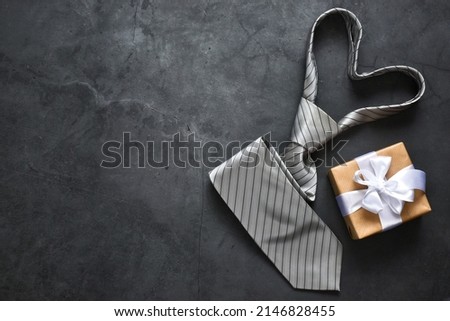 Happy Fathers Day card. Gift box and necktie on gray concrete background. Top view with copy space. Flat lay composition 