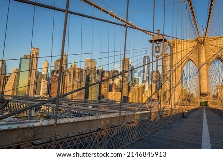 Brooklyn Bridge over East River viewed from New York City Lower Manhattan waterfront at sunrise