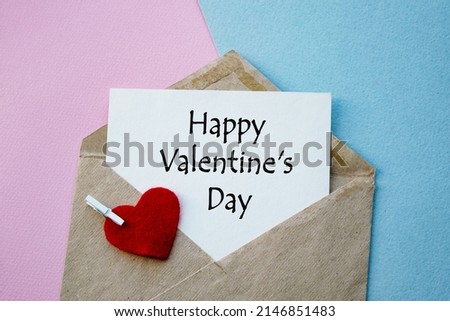An open envelope with the text Happy Valentine's Day, on a pink and blue background with a decor of felt hearts and a flower. Flat lay, top view. LGBT concept.