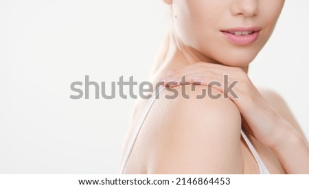 Close-up shot of white-skinned woman with prefect smooth skin who touches her shoulder standing aside against white background | Skin care commercial concept Royalty-Free Stock Photo #2146864453
