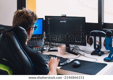 young blond man working sitting in his desk chair at home at his computer.