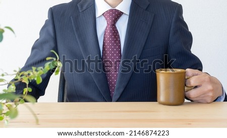 A businessman who takes a break with a cup of coffee.