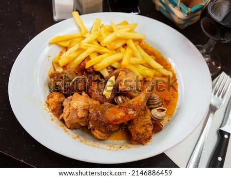 Picture of tasty stewed in sause rabbit with snails, served with french fries at plate