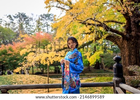 portrait asian woman wearing japanese traditional blue kimono in autumn park.