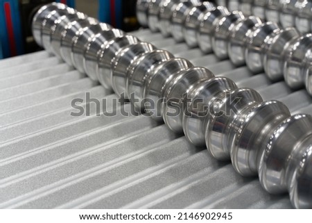 Corrugated metal roofing panel passing through roll former machine Royalty-Free Stock Photo #2146902945