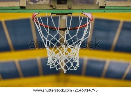 Indoor basketball hoop captured from behind the board, with blue and yellow roof in the background