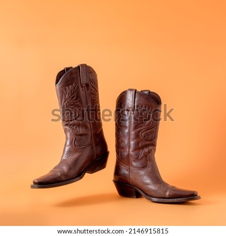 Two elegant classic cowboy boots on an orange clay background. Ranger cowboy concept on a ranch in america usa texas. Royalty-Free Stock Photo #2146915815