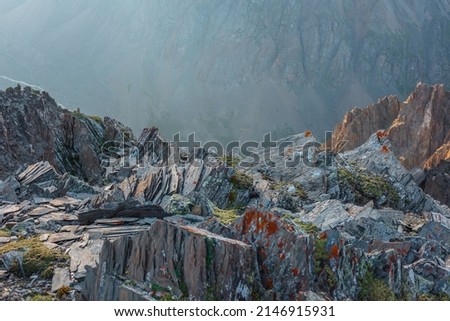 Awesome mountain view from cliff at very high altitude. Scenic alpine landscape with edge of precipice with sharp rocks against large mountain wall. Beautiful scenery on abyss edge with sharp stones. Royalty-Free Stock Photo #2146915931