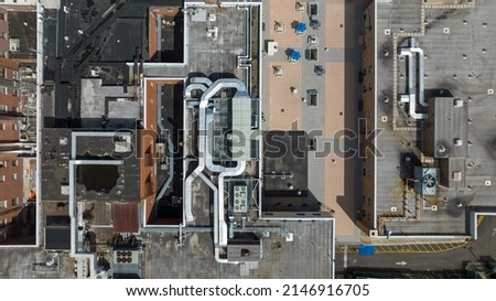 Top down shot directly over an industrial building with large air conditioning fans and ductwork on the roof, taken on a sunny day on Long Island, NY.