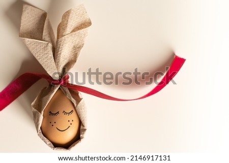 Creative easter egg with a cute face painted on a light background. Happy Easter concept. Top view, mockup, template, copy space. High quality photo