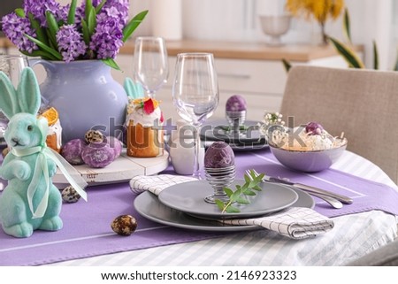 Holder with painted Easter egg and eucalyptus branch on served table