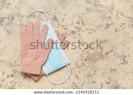 Warm female gloves and medical mask on color color background