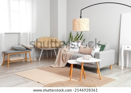 Interior of light living room with coffee tables, sofa and lamp