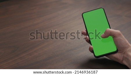 man using smartphone with for online communication on walnut table, wide photo